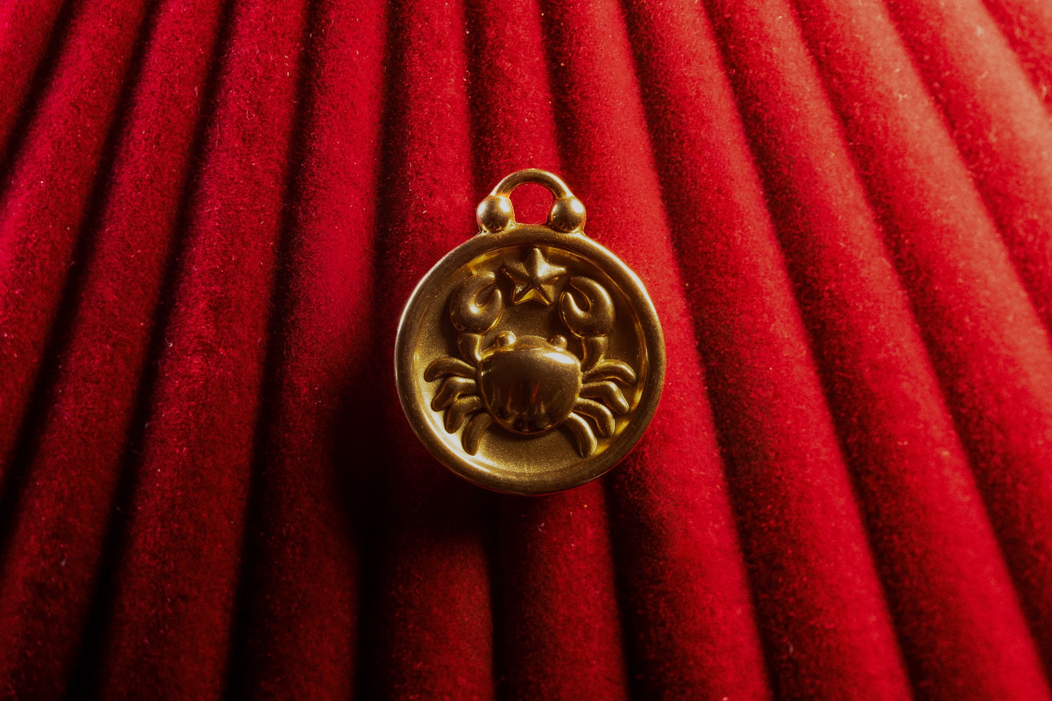 Gold Cancer pendant on a red textured background