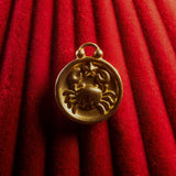 Gold Cancer pendant on a red textured background