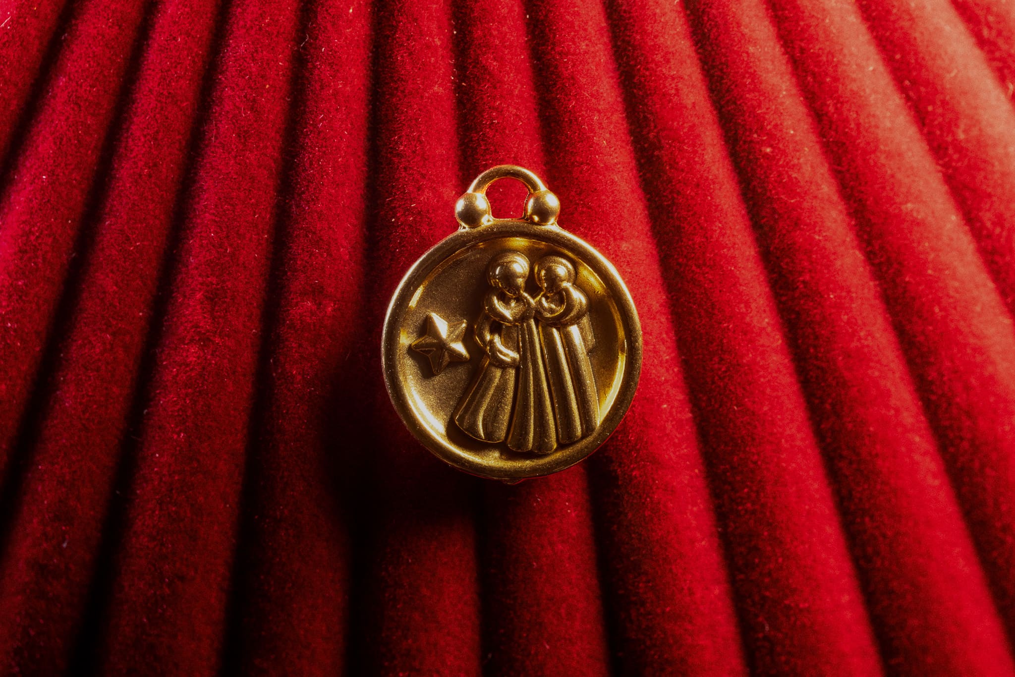 Gold Gemini pendant on a red textured background