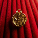 Gold Gemini pendant on a red textured background