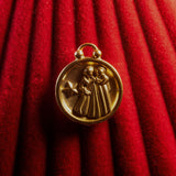 Gold Gemini pendant on a red textured background