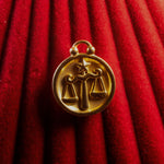 Gold Libra zodiac pendant on a red textured background