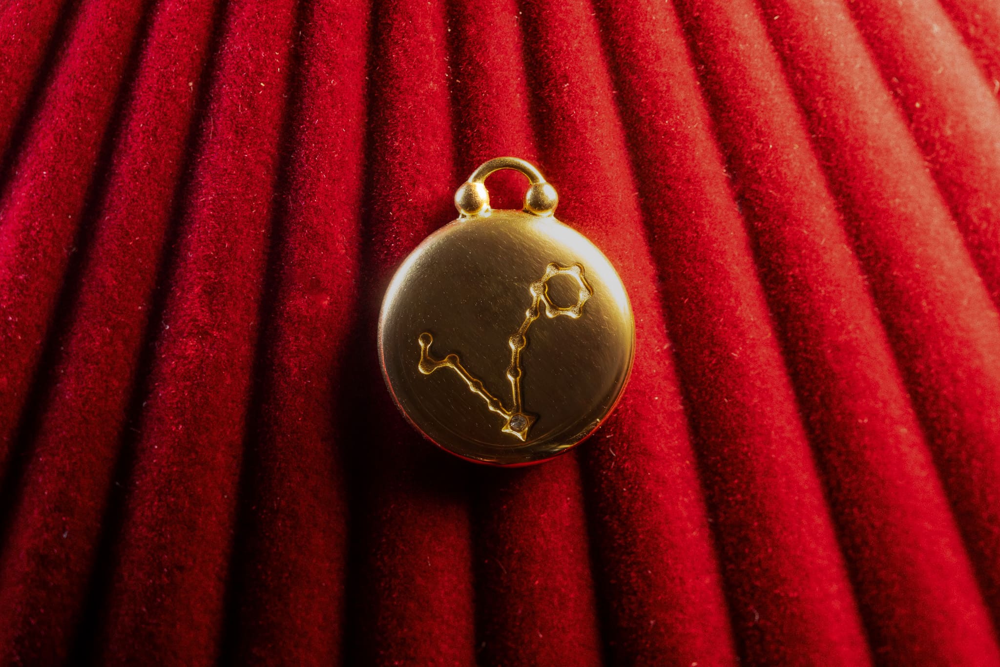 Gold pendant with Pisces constellation on a red textured background