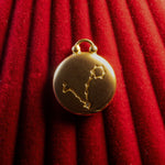 Gold pendant with Pisces constellation on a red textured background
