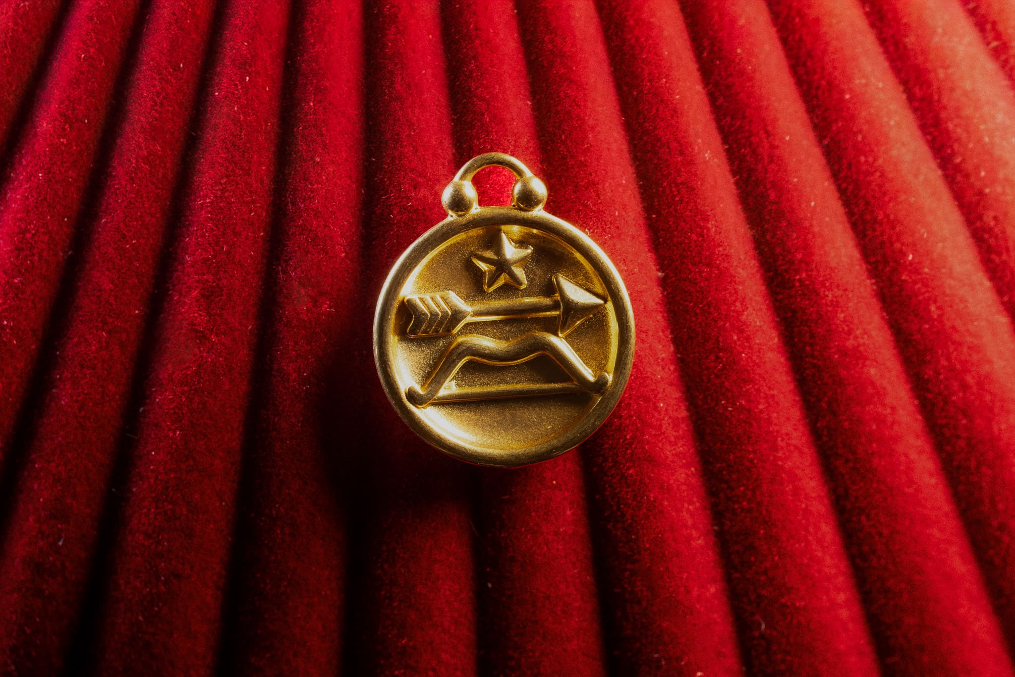 Gold Sagittarius pendant on a red textured background