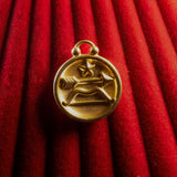 Gold Sagittarius pendant on a red textured background