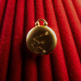 Gold pendant with Aquarius Constellation on a red textured background