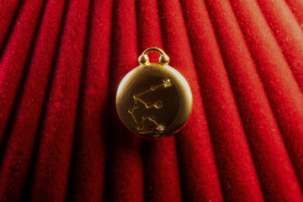 Gold pendant with Aquarius Constellation on a red textured background