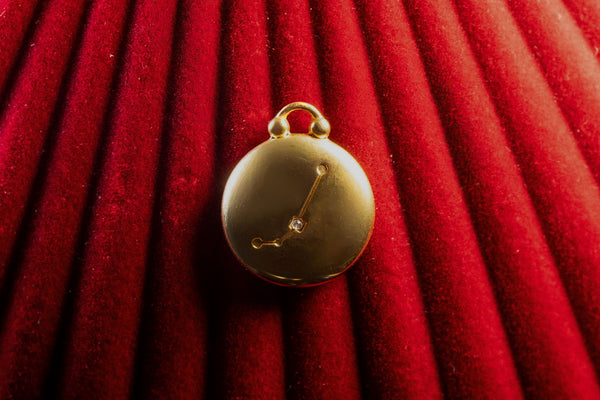Gold pendant with Aries Constellation on a red textured background