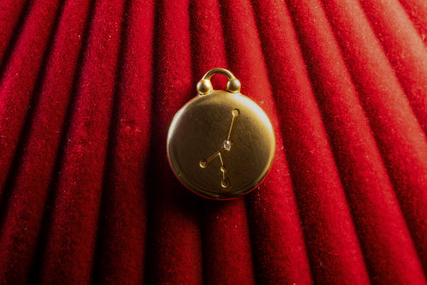 Gold Pendant with a Cancer Constellation on a red textured background