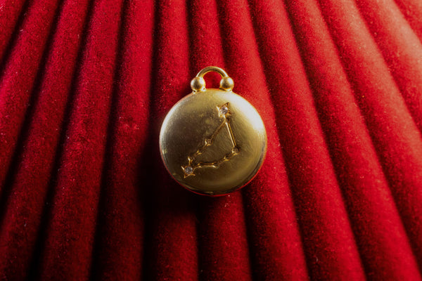 Gold Pendant watch with Capricorn Constellation on a red textured background