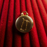 Gold pendant with a Gemini Constellation on a red textured background