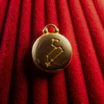 Gold pendant with Leo Constellation on a red textured background