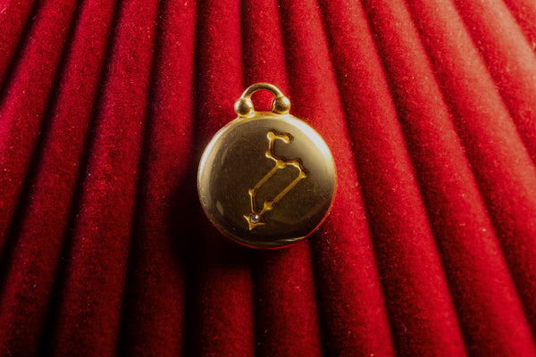Gold pendant with Leo Constellation on a red textured background