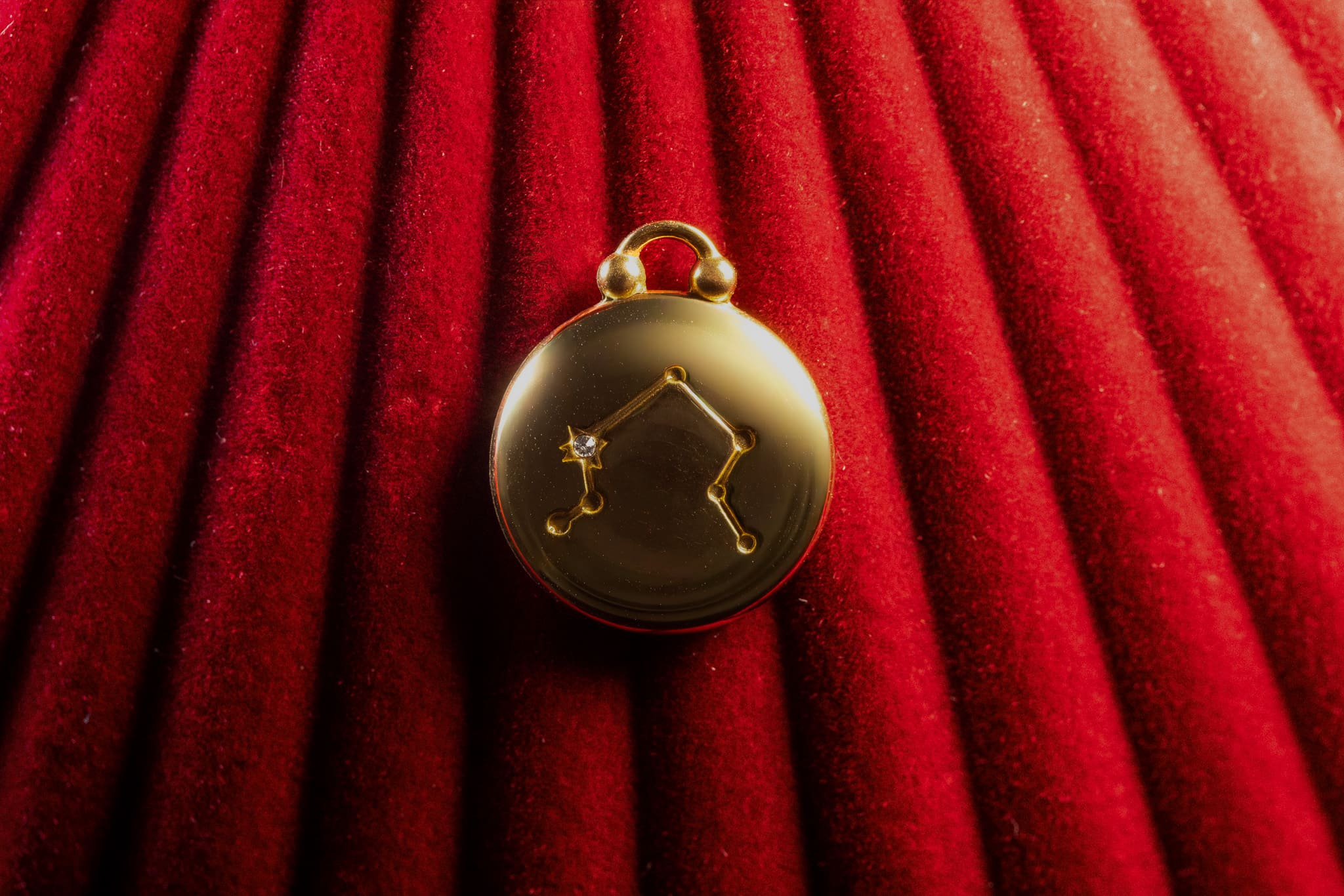 Gold pendant with Libra Constellation on a red textured background