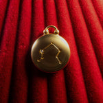 Gold pendant with Libra Constellation on a red textured background