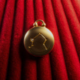 Gold pendant with Libra Constellation on a red textured background
