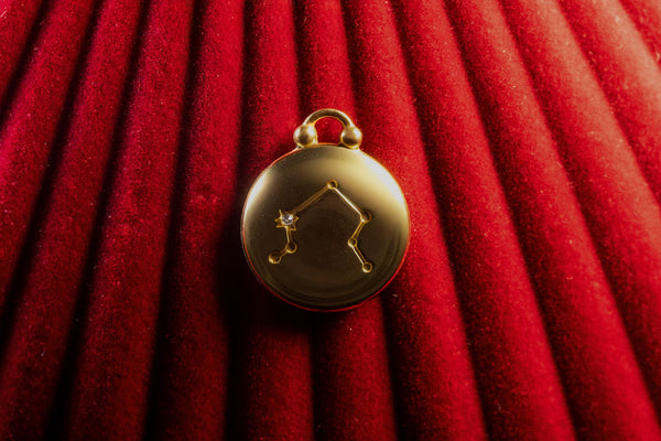 Gold pendant with Libra Constellation on a red textured background