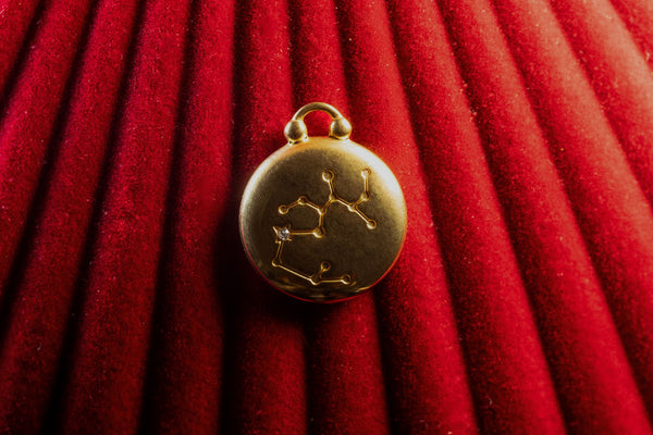 Gold pendant with Sagittarius Constellation on a red textured background