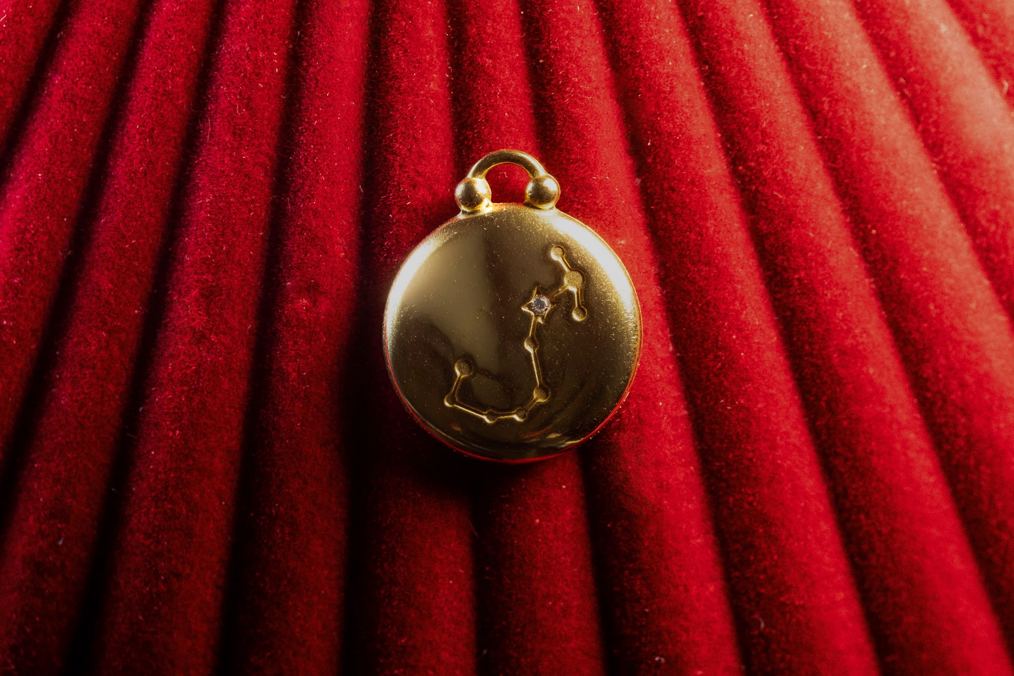 Gold pendant with Scorpio Constellation on a red textured background
